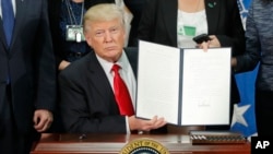 President Donald Trump holds up an executive order for border security and immigration enforcement improvements after signing the order during a visit to the Homeland Security Department headquarters in Washington, Wednesday, Jan. 25, 2017. (AP Photo/Pablo Martinez Monsivais)