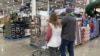 FILE - Shoppers pass displays of goods in a Costco warehouse, Feb. 25, 2024, in Sheridan, Colo. The Trump administration will implement 25% tariffs on Mexican and Canadian goods and a 10% tariff on all Chinese imports on Feb. 1, 2025.