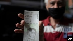 Un hombre muestra un nuevo billete de 200.000 bolívares - la moneda oficial - después de retirarlo de un banco en Caracas, el 16 de marzo de 2021.