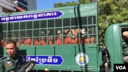 Youth activist Kong Raiya waves his hand as a van carries him along with other prisoners from Prey Sar prison to the Phnom Penh Municipal Court, in Phnom Penh, on Nov. 26, 2019. (Hul Reaksmey/VOA Khmer)