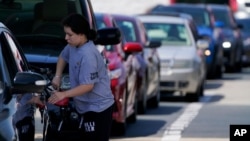 A customer pumps gas at Costco, as others wait in line, in Charlotte, N.C., May 11, 2021.