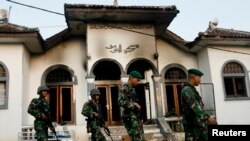 Sejumlah personel TNI melewati masjid milih jemaah Ahmadiyah yang dibakar massa di Desa Ciampea, Jawa Barat, 2 Oktober 2010.