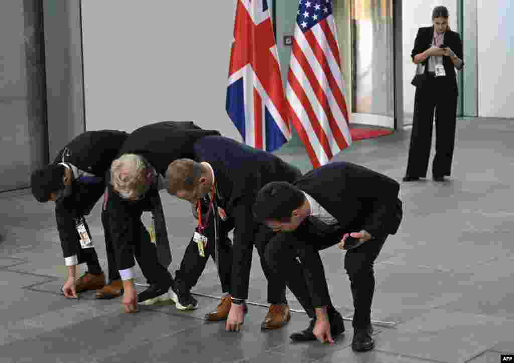 Staff members put names on the floor for the family photo of the "Quad meeting" held by the German Chancellor, the U.S. President, the French President and the British Prime Minister at the Chancellery in Berlin.