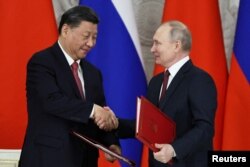 Presiden Rusia Vladimir Putin berjabat tangan dengan Presiden China Xi Jinping saat upacara penandatanganan setelah pembicaraan mereka di Kremlin di Moskow, Rusia 21 Maret 2023. (Foto: via Reuters)