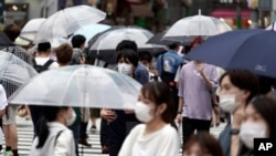 People wearing a protective face mask to help curb the spread of the coronavirus walk at Shibuya pedestrian crossing, July 9, 2020, in Tokyo.