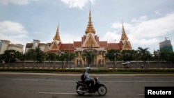 រូបឯកសារ៖ អ្នក​បើក​ម៉ូតូ​ម្នាក់​បើក​តាមផ្លូវនៅខាងមុខ​​​អគារ​វិមាន​រដ្ឋសភា​ជាតិ​នៅ​រាជធានី​ភ្នំពេញ​កាល​ពី​ថ្ងៃ​ទី​២៦ ខែ​សីហា ឆ្នាំ​២០១៤។