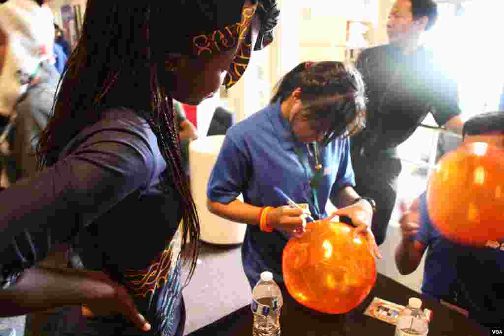 A member of the Cambodian robotics team signs on another country's team member's shirt after the closing of the First Global Challenge robotics competition in Washington, DC, Tuesday, July 18, 2017. (Nem Sopheakpanha/VOA Khmer)
