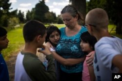 Olga Lopatkina memeluk anak angkatnya di sebuah taman di Loue, Prancis barat, Sabtu, 2 Juli 2022. (Foto: AP)