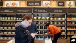 FILE - Shoppers roam through an Amazon Go store.