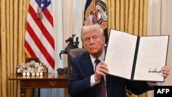 Donald Trump brandit un décret dans le bureau ovale de la Maison Blanche à Washington, DC, le 23 janvier 2025.