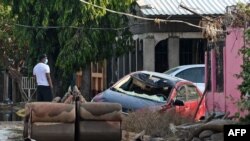 Un hombre observa un auto destruido y muebles cubiertos de lodo tras el paso del huracán Eta en la municipalidad de La Lima, en el departamento hondureño de Cortés.