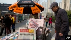 A man looks at a newsstand with a copy of the day's Global Times displayed on a basket in Beijing, China, Tuesday, April 5, 2016.