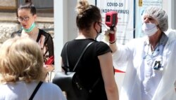 A medical staff attends to people as they arrive to test for coronavirus, at a hospital in Sarajevo, Bosnia and Herzegovina, 01 July 2020.
