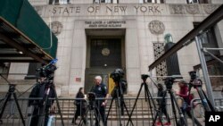 Gente pasa frente al tribunal y cámaras y equipos instalados por la prensa a la espera de la resolución del gran jurado sobre Donald Trump, el 23 de marzo de 2023. 