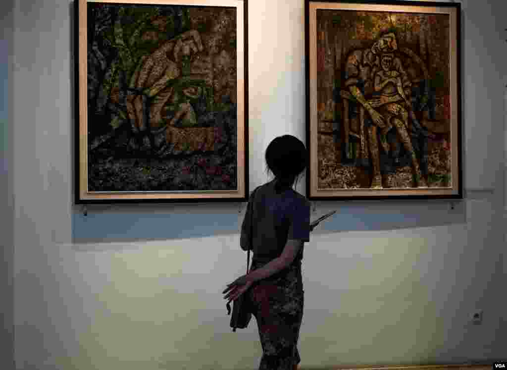 សាធារណជន​សញ្ជឹង​មើល​​ផ្ទាំង​គំនូររបស់​ វិចិត្រករ សាង ណាន់ ដែលបង្ហាញនូវភាពឈឺចាប់​ និង​ក្តីសង្ឃឹមរបស់​ប្រជាជនខ្មែរ​ដែលបានរស់ក្នុងសម័យខ្មែរក្រហម​ និង​តស៊ូក្នុងជីវិតបច្ចុប្បន្ន​។​ គំនូរទាំង១១ ផ្ទាំងរបស់លោក​ត្រូវបាន​តាំង​បង្ហាញ​​នៅកម្មវិធីមហោស្រពភាពយន្តអន្តរជាតិកម្ពុជាលើកទី៩, នៅរាជធានីភ្នំពេញ, នៅថ្ងៃទី១២ ខែមីនា​ ឆ្នាំ២០១៩។ (ខាន់ សុគុំមនោ/VOA)