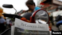 ស្ត្រីម្នាក់​​ទិញ​កាសែត​ The Cambodia Daily ដែល​បោះពុម្ព​ផ្សាយ​លេខ​ចុងក្រោយ​ នៅ​តូប​លក់​កាសែត​មួយ​ក្នុង​រាជធានី​ភ្នំពេញ​ ប្រទេស​កម្ពុជា​ ថ្ងៃទី៤​ ខែ​កញ្ញា​ ឆ្នាំ២០១៧។​ (Reuters / Samrang Pring) 