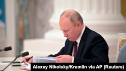 ولادیمیر پوتین، رییس جمهور روسیه، هنگام امضای اسنادی که بر اساس آن،‌ مسکو مناطق جدایی طلب اوکراین را به رسمیت شناخت