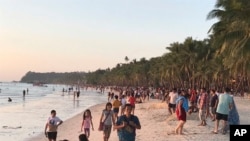 Visitors gather along the beach during sunset in Boracay island, Philippines, Friday, Oct. 26, 2018. Tourists sailed to the popular destination on the first day officials reopened the resort to visitors