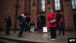 FILE - People wait for their turn to enter Stockholm's City Hall that temporarily served as a COVID-19 vaccination site, in Stockholm, Sweden, Feb. 21, 2021. 