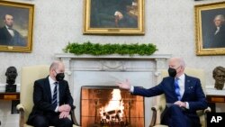 President Joe Biden, right, gestures during a meeting with German Chancellor Olaf Scholz in the Oval Office of the White House, in Washington, Feb. 7, 2022.