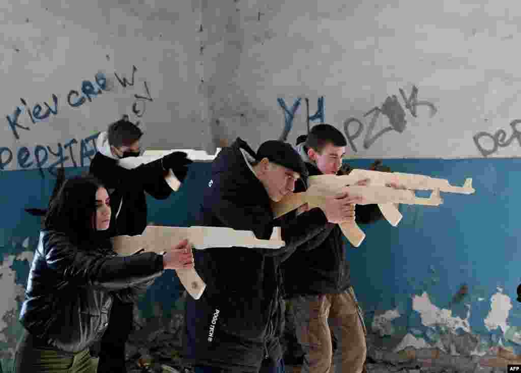 Civilians train to hold wooden replicas of Kalashnikov rifles at an abandoned factory in the Ukrainian capital of Kyiv.