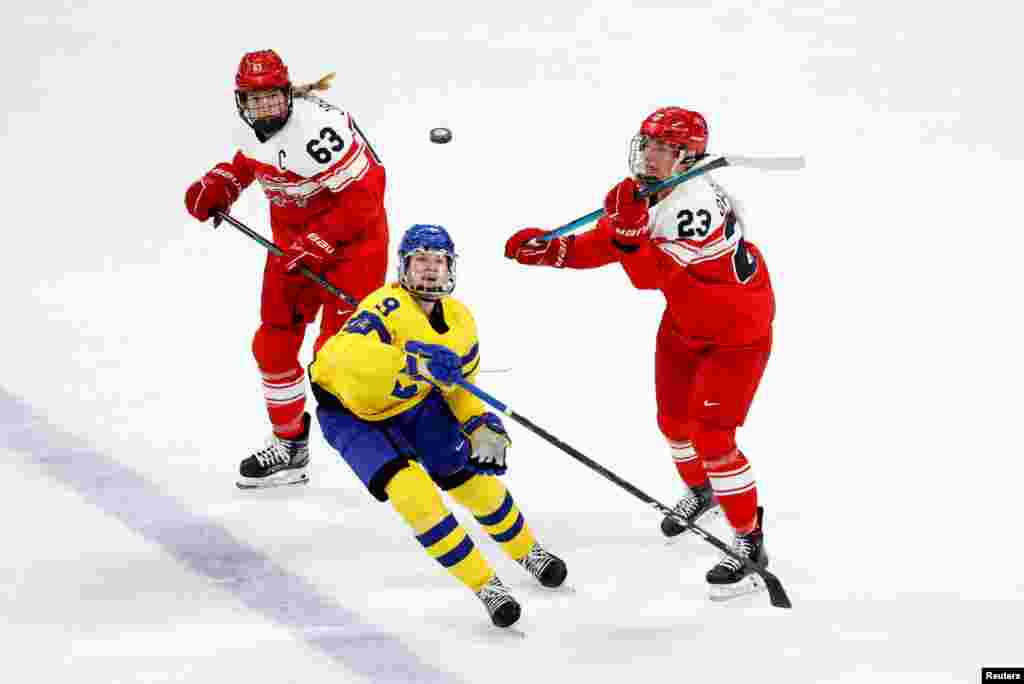Jessica Adolfsson of Sweden go for the puck with Julie Oksbjerg of Denmark and Josefine Jakobsen of Denmark during the women's preliminary round group B match of 2022 Beijing&nbsp; Olympics ice hockey competition between Sweden and Denmark at the Wukesong Sports Center.