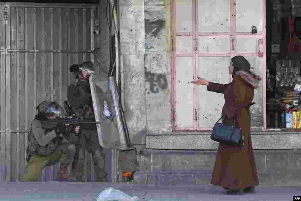 A woman gestures at Israeli security forces firing rubber-bullets to disperse Palestinian stone-throwers amid clashes in the West Bank town of Hebron.