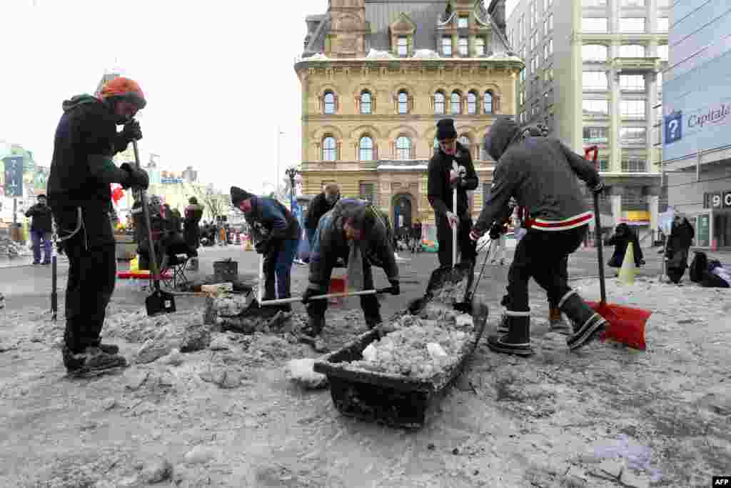 Protesters and supporters clear snow and ice in front of Prime Minister Justin Trudeau's office as demonstrators continue to protest the vaccine mandates, in Ottawa, Canada.