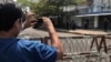 FILE - A journalist and a police officer take pictures of each other as people protest against the military coup in Yangon, Myanmar, Feb. 23, 2021.