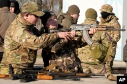 Instruktor pokazuje ženi kako da koristi automatsku pušku "Kalašnjikov", u sklopu treninga ekstremno desne grupe, u Kijevu, 13. februara 2022.