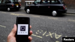 FILE - A photo illustration shows the Uber app logo displayed on a mobile telephone, as it is held up for a posed photograph in central London, Britain Oct. 28, 2016. 