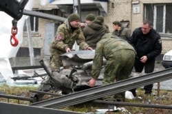 Workers prepare to load the debris of a rocket onto a truck the aftermath of Russian shelling in Kyiv, Ukraine, Feb. 24, 2022.