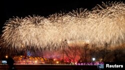 People watch as fireworks explode over the National Stadium, also known as the Bird's Nest, at the end of the closing ceremony of the Beijing 2022 Winter Olympics, in Beijing, China February 20, 2022. REUTERS/Carlos Garcia Rawlins