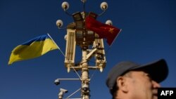 一名男子走過北京天安門廣場燈柱上懸掛的中國與烏克蘭國旗。（2013年12月5日）