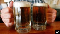 FILE - A bartender serves two mugs of beer at a tavern in Montpelier, Vermont, June 29, 2004.