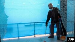 یک کارگر در حال جمع کردن شیشه های شکسته شده یک فروشگاه در حمله راکتی به اربیل در اقلیم کردستان عراق. ۱۶ فوریه ۲۰۲۱