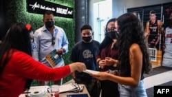 Lorena Torres (2R) madre de Valentina Jiménez (derecha) de 15 años es asistida por el personal de Miami Heat durante un evento de vacunación COVID-19 organizado por Miami Heat en FTX Arena en Miami, el 5 de agosto de 2021.