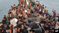 FILE - Migrants wait to be be rescued by Acehnese fishermen on their boat on the sea off East Aceh, Indonesia, May 20, 2015.