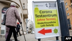 An elderly woman walks past a coronavirus testing site in the city center in Halle/Saale, eastern Germany, Jan. 25, 2022.