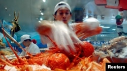 澳大利亞悉尼海鮮市場的一名商販在展示他烹飪的龍蝦。(資料圖片）