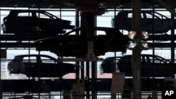 FILE - E-Golf electric cars hang in the assembly line during the official production start in the German car manufacturer Volkswagen Transparent Factory (Glaeserne Manufaktur) in Dresden, eastern Germany.