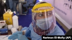  In this June 17, 2020 file photo, a health worker wearing protective gear prepares to take samples from people lining up in their cars to test for the coronavirus at a drive-through COVID-19 testing center at Ain Shams University in Cairo, Egypt. 