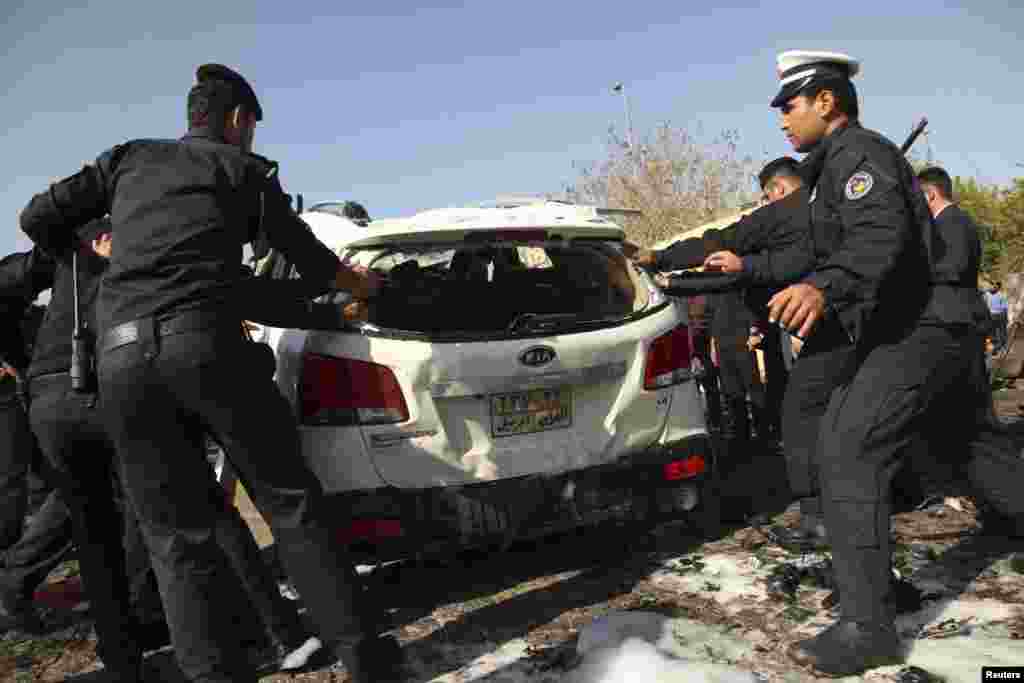 Kurdish security forces inspect one of the cars damaged in the attack in Irbil, Nov.19, 2014.