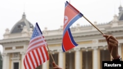 Warga memegang bendera AS dan Korea Utara di Hanoi, Vietnam, 28 Februari 2019. (Foto: REUTERS/Kham)