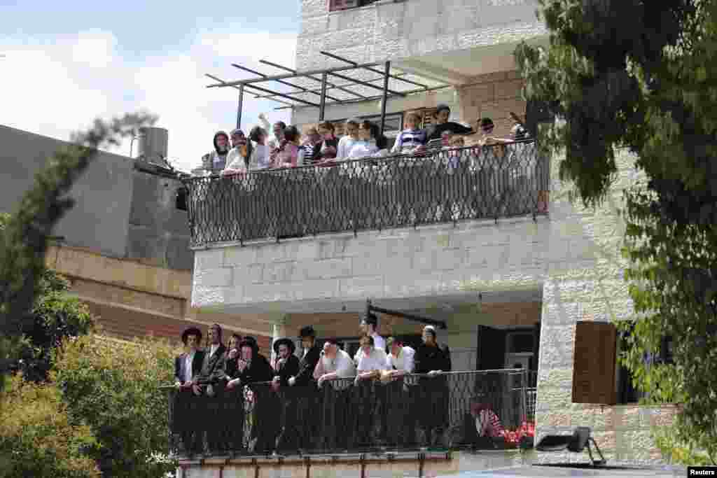 Residents stand on their balconies looking at the scene of a suspected attack, in Jerusalem, Aug. 4, 2014.