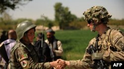 FILE - A U.S. soldier, right, shakes hands with an Afghan National Army soldier before the opening ceremony for a newly completed mosque in southern Kandahar province, April 1, 2011, where the U.S. is funding its rebuilding.