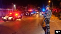A Federal police officer stands on guard at the area where at least five people including a ministerial police officer were killed in Puerto Juarez, Cancun, Quintana Roo State, Mexico, on July 27, 2018. - A journalist was murdered Tuesday in southeast…