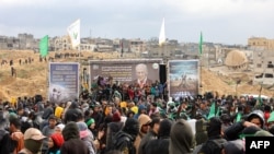 Palestinian Hamas fighters and people gather at the site of the handing over of the bodies of four Israeli hostages in Khan Yunis in the southern Gaza Strip on February 20, 2025.