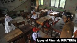 Siswa dan guru memakai masker pelindung setelah pemerintah Indonesia membuka kembali sekolah dengan menerapkan proses pembelajaran tatap muka di tengah wabah Covid-19 di Pariaman, Provinsi Sumatera Barat, 13 Juli 2020. (Foto ilustrasi: Antar /Iggoy el Fitra/via Reuters)