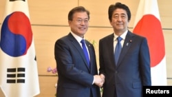 South Korea's President Moon Jae-in, left, shakes hands with Japan's Prime Minister Shinzo Abe before their meeting at Abe's official residence in Tokyo, May 9, 2018. 